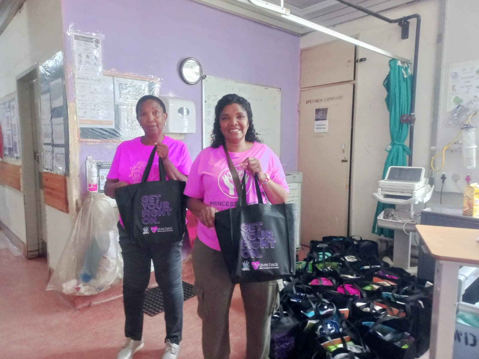 Foundation representatives hold care bags beside prepared outreach supplies